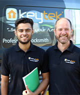 two locksmiths stood smiling outside locksmith van